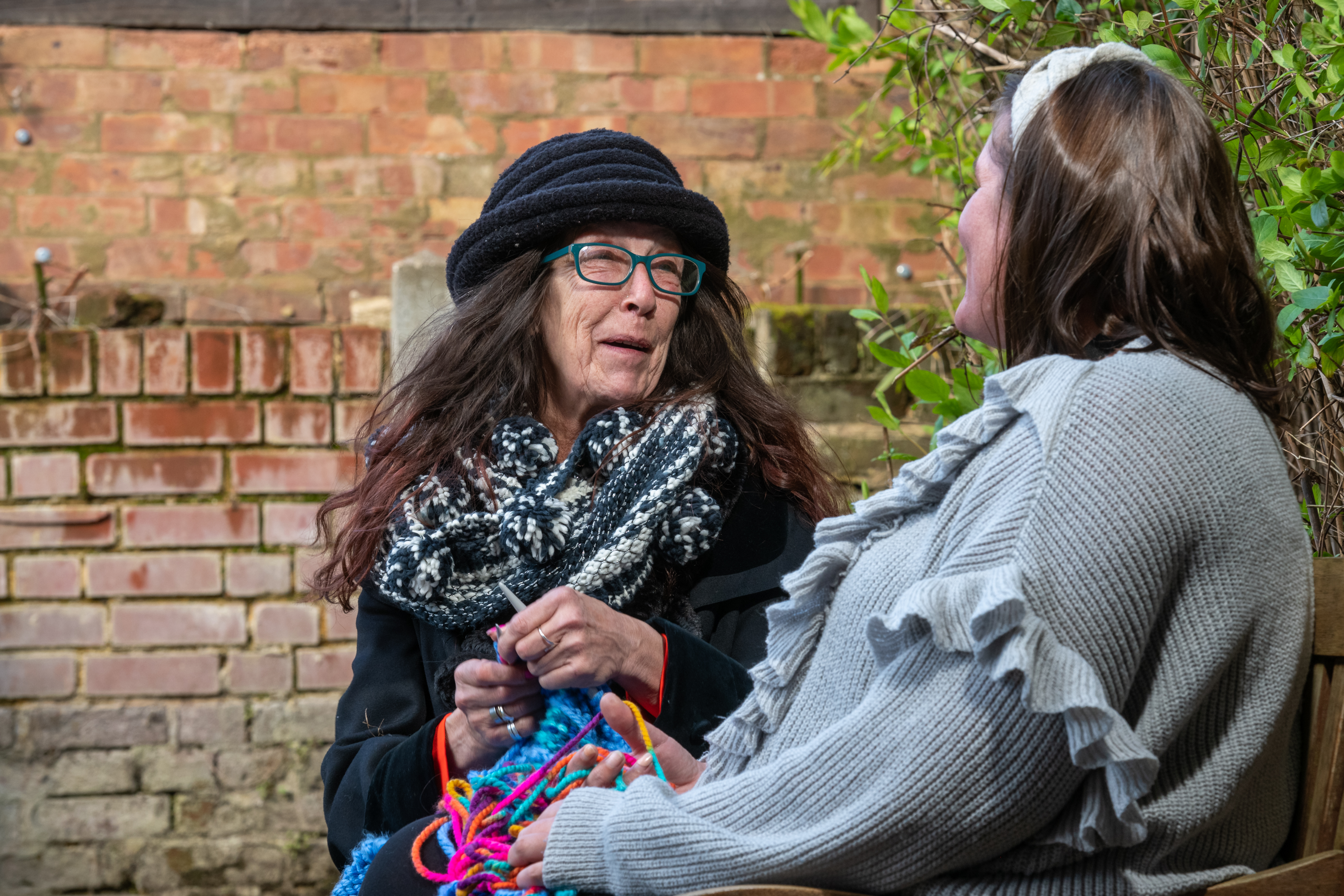 Two people knitting in a garden