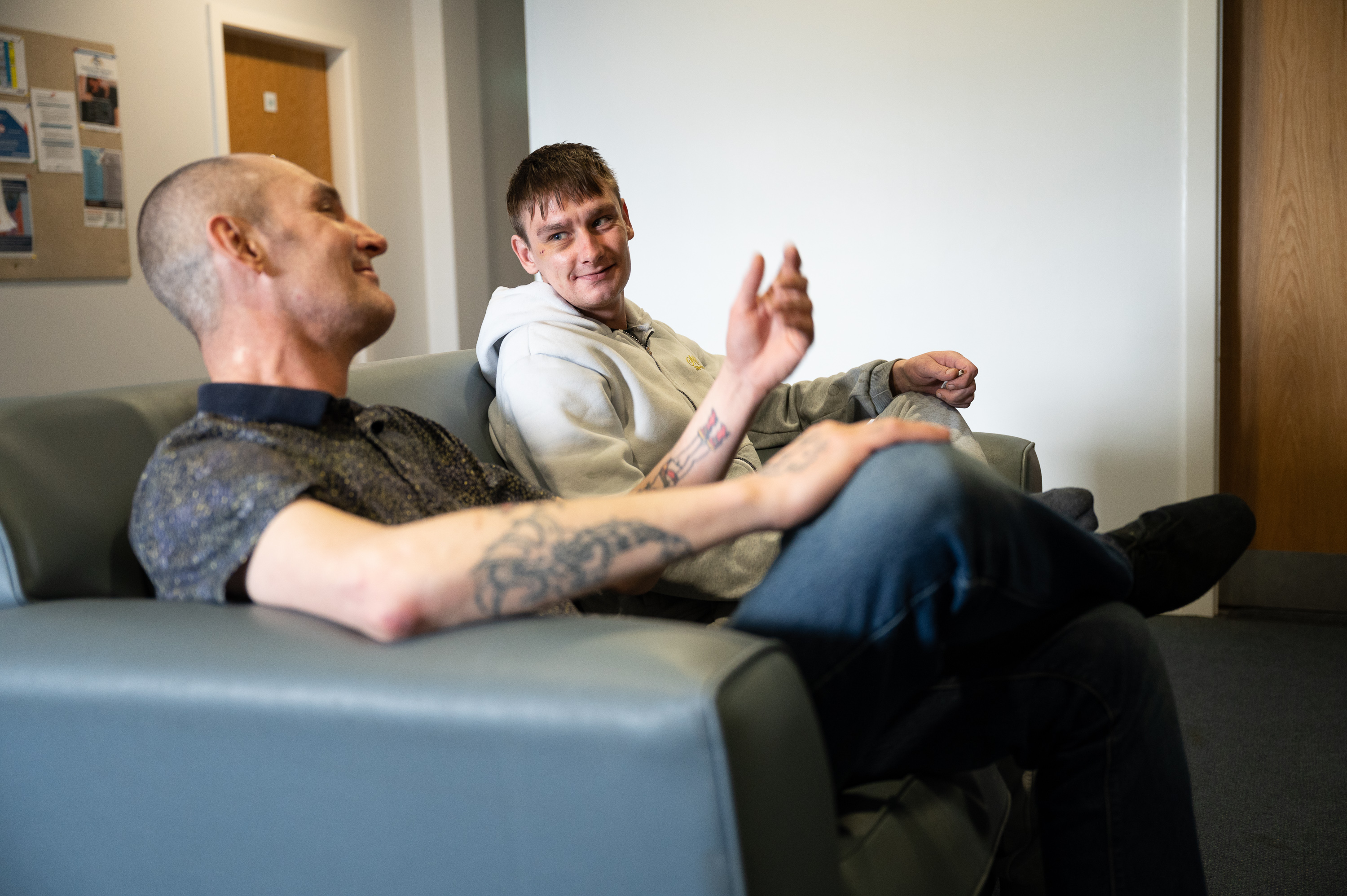 Two people sit chatting on a sofa