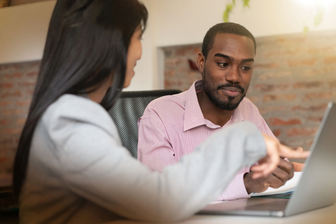Experienced colleague mentoring a board trainee during a meeting.