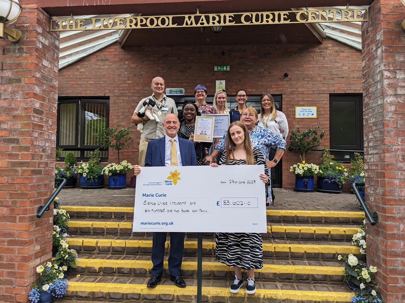 Colleague holding up cheque for marie curie that riverside had raised