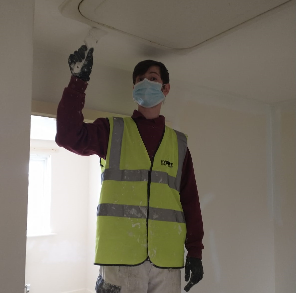 Apprentice painting ceiling of tenant's home