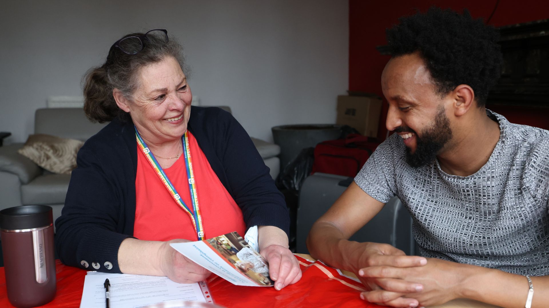 A Riverside staff member speaking to a resident, sat at a dining table.