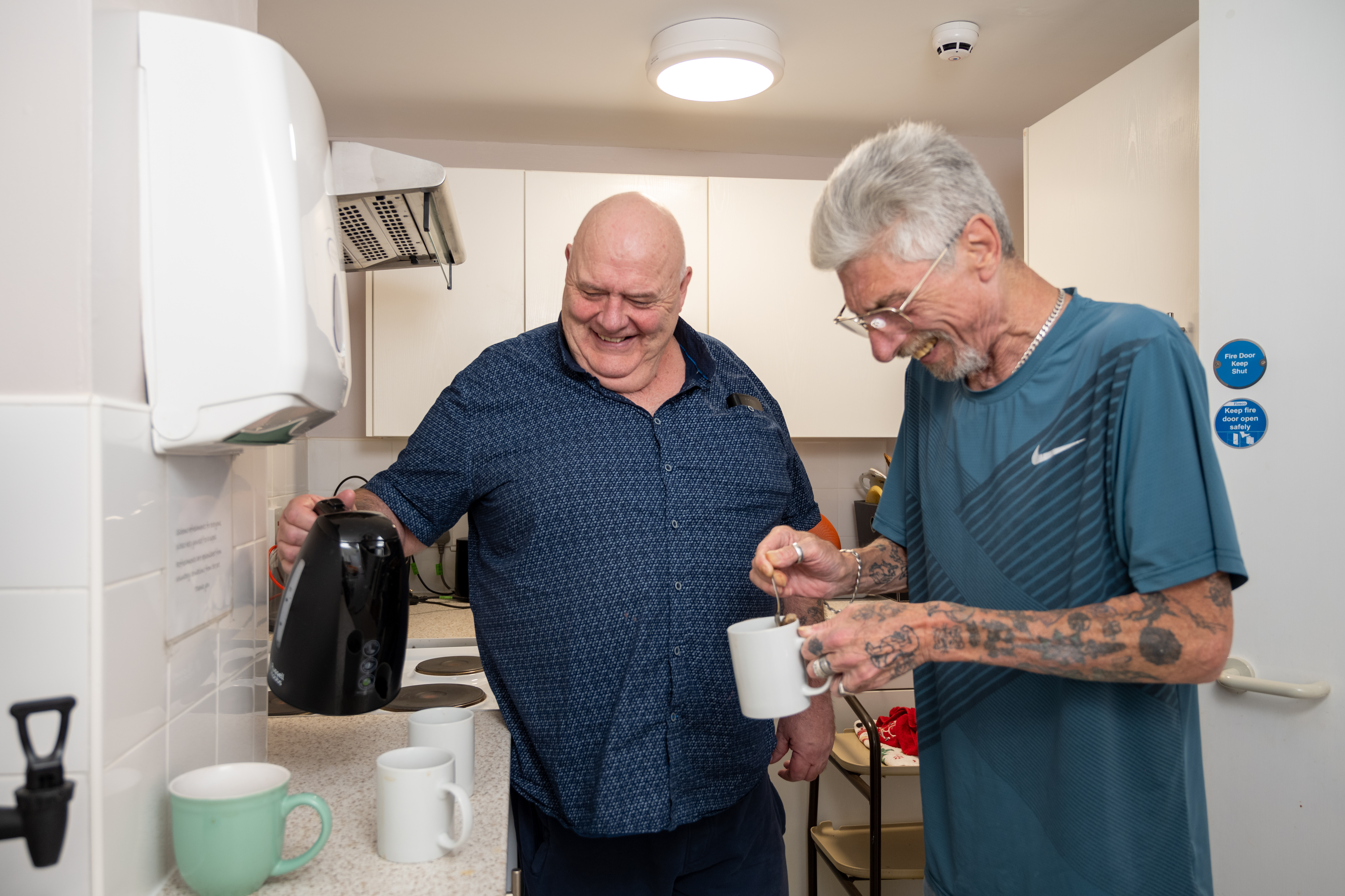Two people laughing together in a kitchen