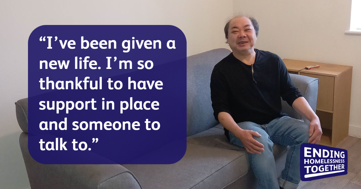Person seated on a sofa in a sparsely furnished room, with a quote displayed in a dark blue speech bubble reading, “I’ve been given a new life. I’m so thankful to have support in place and someone to talk to.” The Ending Homelessness Together logo appears in the bottom right corner.