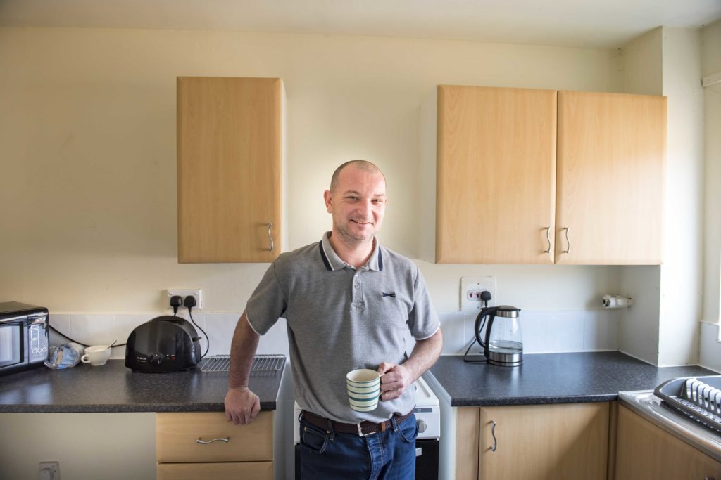 A smiling Riverside customer stood in his kitchen, holding a mug