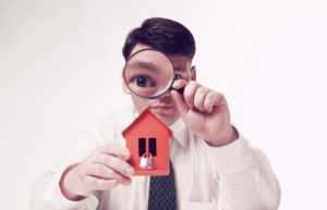 Man with magnifying glass house and paper