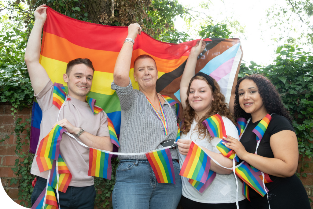 Colleagues at a bed every night LGBTQ+ service in Manchester hold Pride flags.