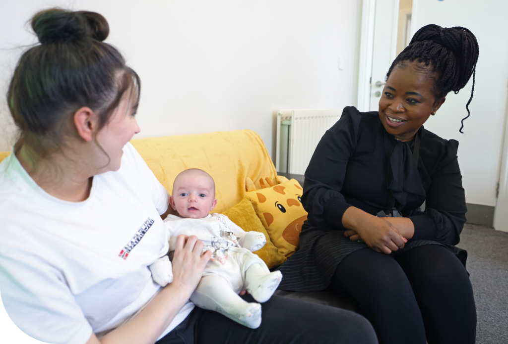 A Riverside colleague sits with a customer and her baby